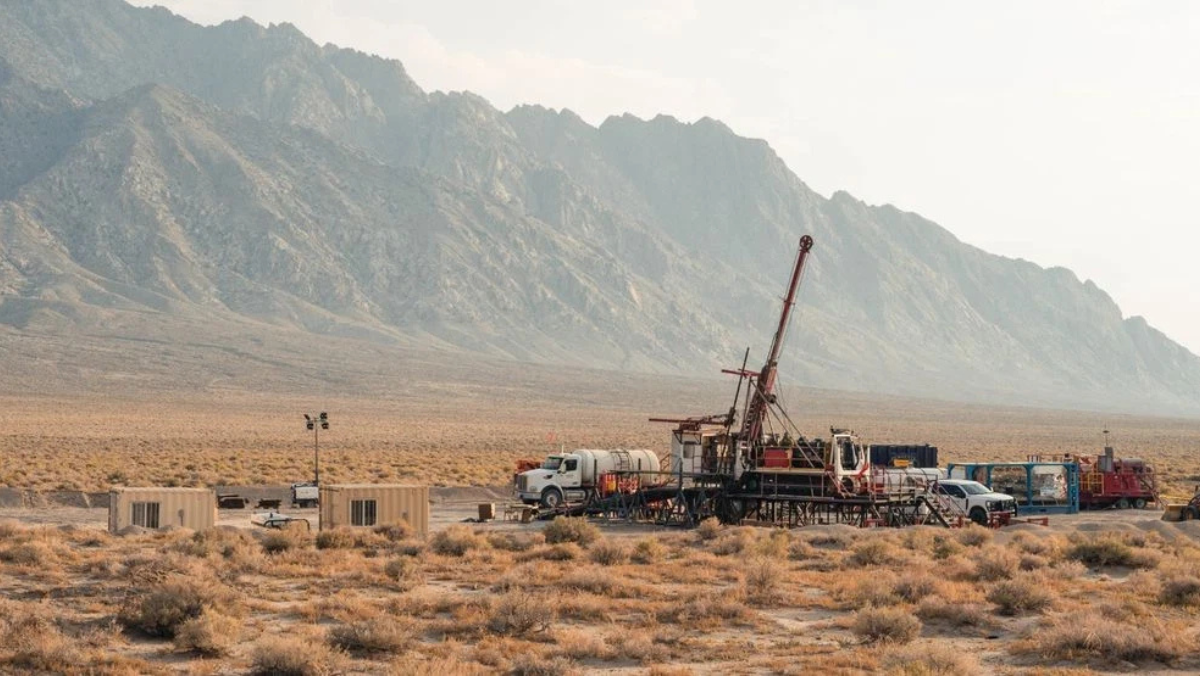 Remote Nevada geothermal drill site with equipment and trucks set against mountain range during exploration work.