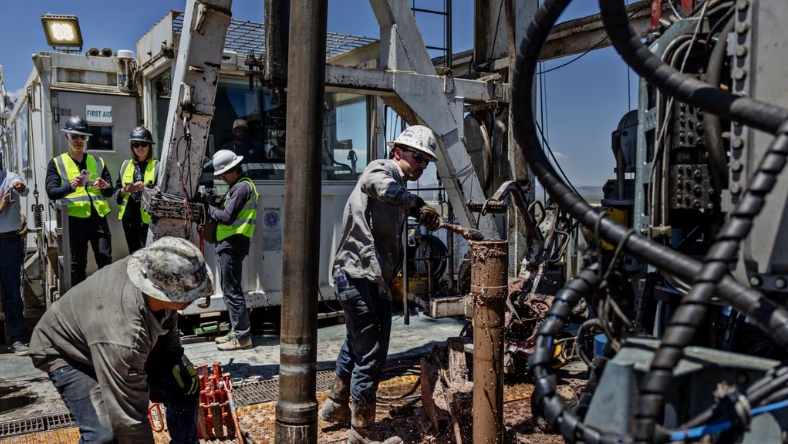 Workers operating geothermal drilling machinery during deep well construction
