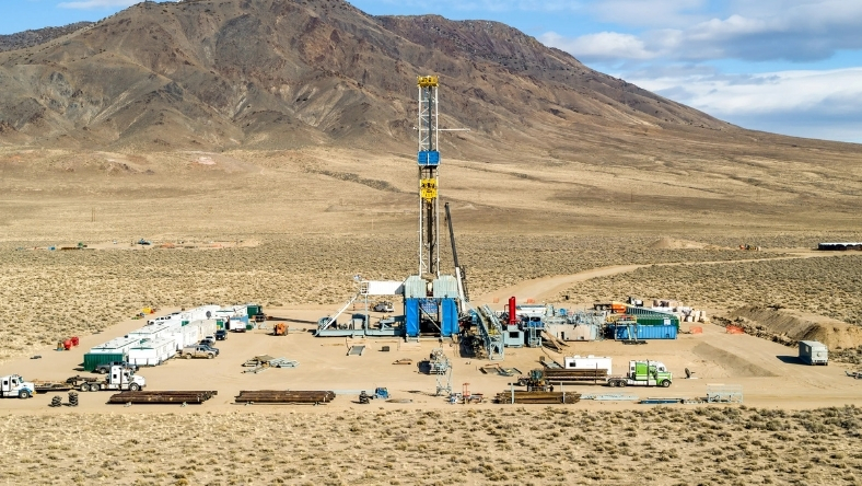 Geothermal drilling rig operating at a remote site in a desert landscape