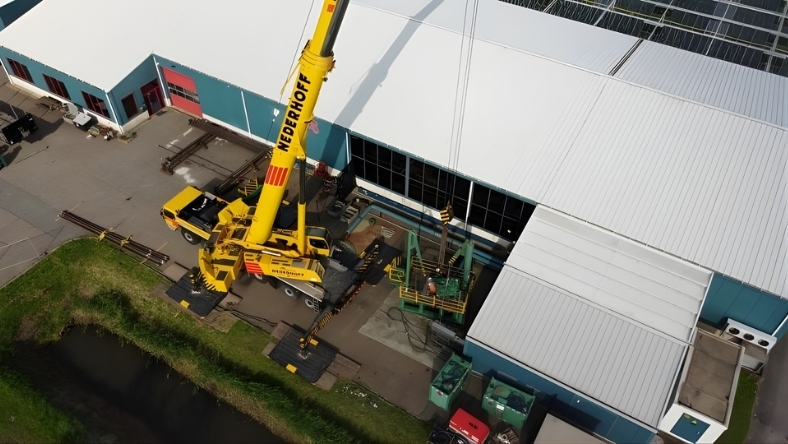 Heavy lift crane positioned beside industrial building near canal